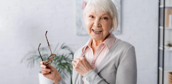 Heureuse femme âgée avec des lunettes souriant à la caméra, bannière — Photo de stock