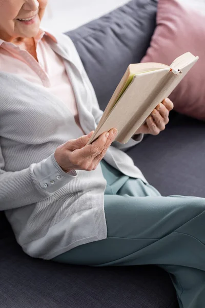 Vista recortada del libro en manos de una mujer mayor sonriente - foto de stock