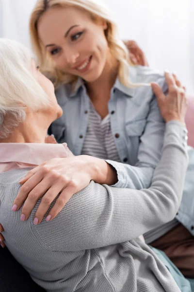 Erwachsene Frau auf verschwommenem Hintergrund umarmt Mutter — Stockfoto