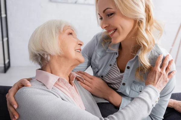 Mujer mayor mirando a su hija sonriente en casa - foto de stock