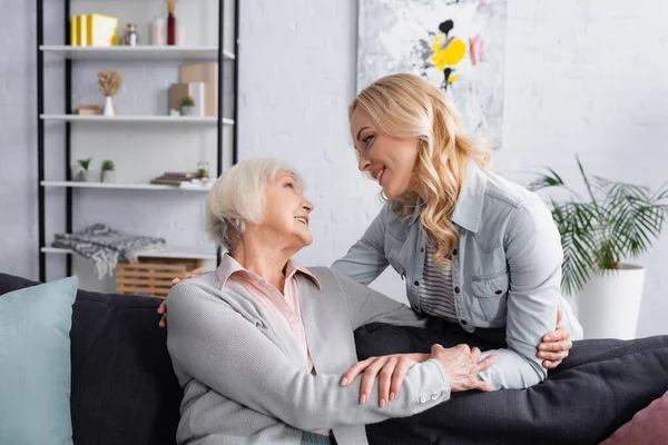 Seniorin lächelt Tochter zu Hause auf Couch an — Stockfoto