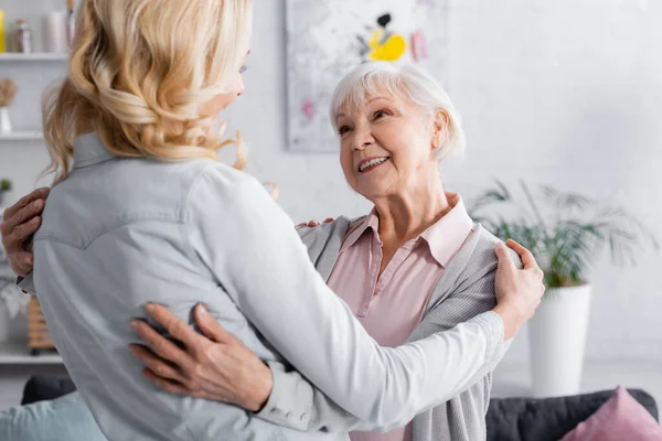 Lächelnde Frau schaut verschwommene Tochter zu Hause an — Stockfoto