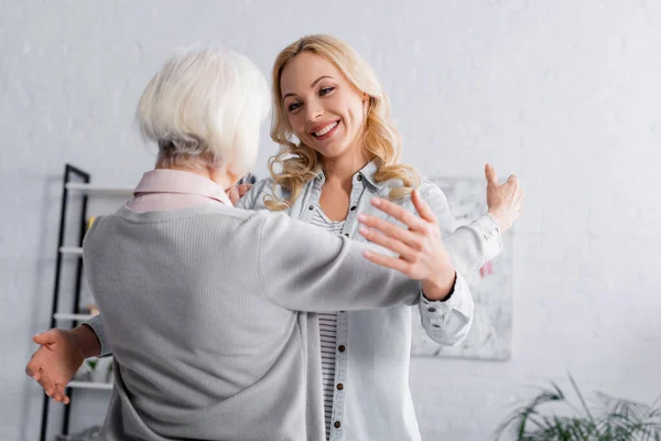 Lächelnde Frau schaut ältere Mutter zu Hause an — Stockfoto