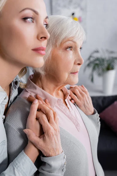 Elderly parent holding hands of daughter on blurred foreground at home — Stock Photo