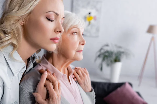 Femme avec les yeux fermés tenant les mains de la mère sur fond flou — Photo de stock