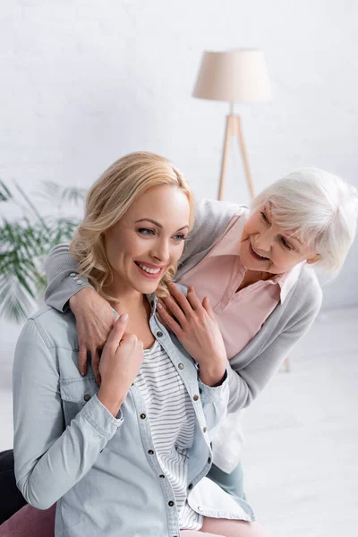 Heureuse femme aux cheveux gris debout près de fille adulte — Photo de stock