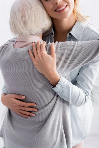 Attenta donna adulta abbracciando genitore dai capelli grigi — Foto stock