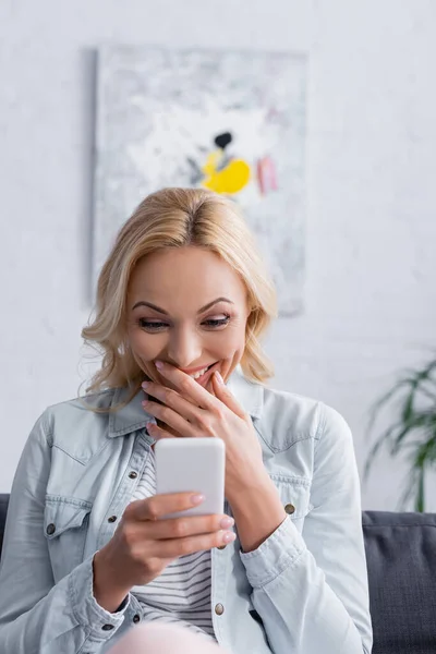 Aufgeregte Frau mit Smartphone im verschwommenen Vordergrund — Stockfoto