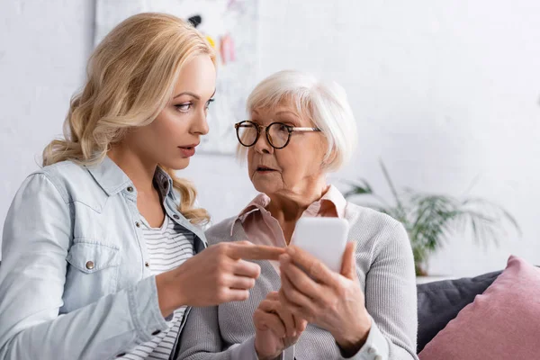 Donna che parla con la madre anziana con smartphone in primo piano sfocato — Foto stock