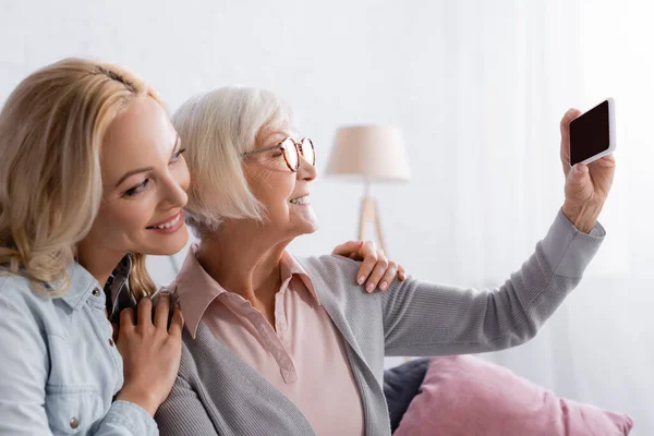 Lächelnde ältere Eltern machen Selfie mit Handy in der Nähe ihrer Tochter — Stockfoto