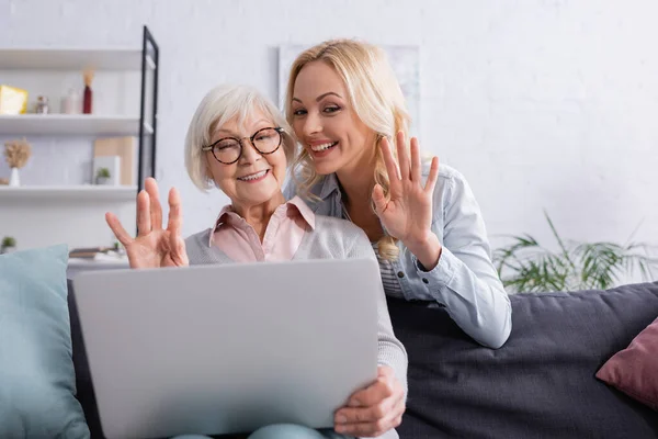 Sonriente hija y madre teniendo videollamada en el portátil - foto de stock