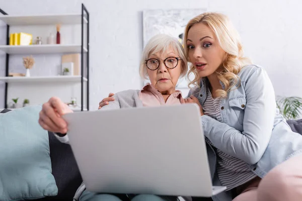 Aufgeregte Frau benutzt Laptop bei älterer Mutter zu Hause — Stockfoto