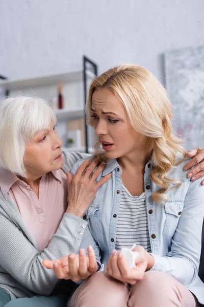 Disappointed woman with napkin sitting near senior mother — Stock Photo