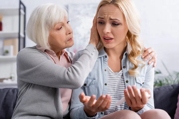 Elderly mother calming displeased daughter with napkin at home — Stock Photo