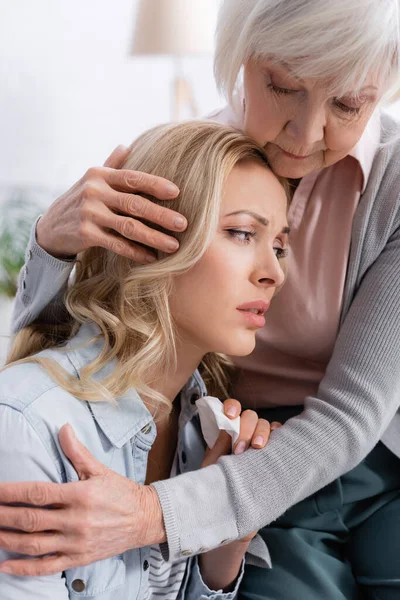 Anciana madre calmar y abrazar molesto hija en casa — Stock Photo