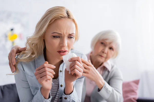 Displeased woman sitting near senior mother on blurred background — Stock Photo