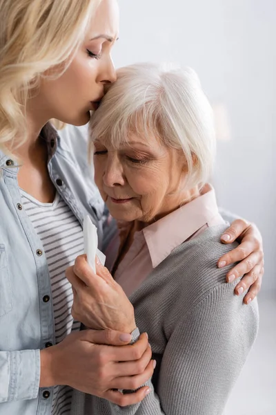 Дочка цілується незадоволена старша жінка тримає серветку — стокове фото