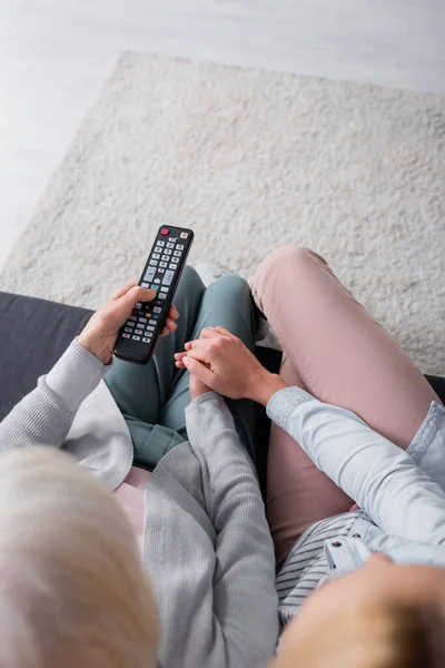 Vue aérienne de la femme tenant la main d'un parent aîné avec télécommande — Photo de stock