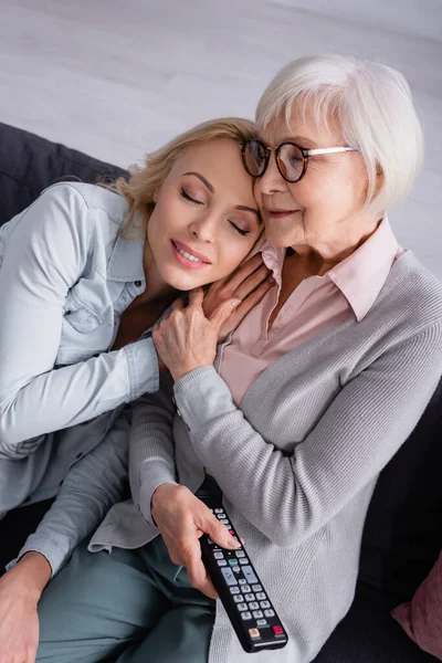 Donna seduta vicino alla madre anziana con telecomando — Foto stock