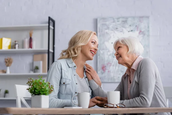 Fröhliche Frauen reden im Wohnzimmer neben Tassen und Brillen — Stockfoto