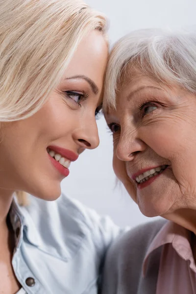 Vista de cerca de la mujer sonriente mirando a la madre anciana - foto de stock