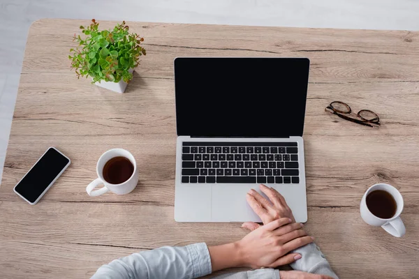 Visão superior da mãe usando laptop perto da filha e chá na mesa — Fotografia de Stock