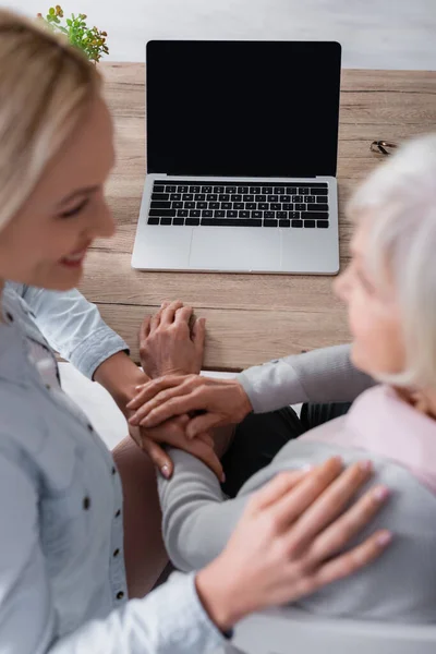 Laptop with blank screen near women on blurred foreground at home — Stock Photo