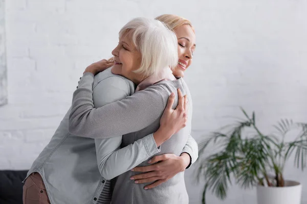 Smiling parent with closed eyes hugging daughter — Stock Photo