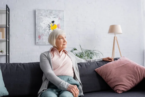 Grauhaarige Frau schaut im Wohnzimmer weg — Stockfoto