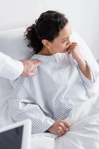 Doctor touching shoulder of upset african american woman, blurred foreground — Stock Photo