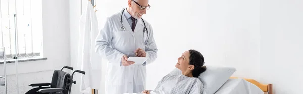 Médico positivo falando com a mulher americana africana sorridente no hospital, banner — Fotografia de Stock