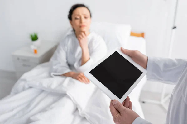 Tablette numérique avec écran blanc dans les mains du médecin près de la femme afro-américaine sur fond flou — Photo de stock