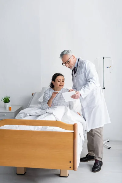 Médecin souriant montrant tablette numérique à la femme afro-américaine à l'hôpital — Photo de stock