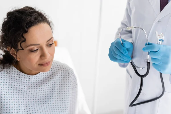 Donna afro-americana vicino al medico in guanti di lattice con stetoscopio in mano — Foto stock