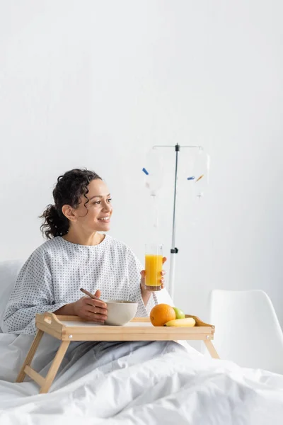 Gioiosa donna afroamericana distogliendo lo sguardo mentre fa colazione in clinica — Foto stock