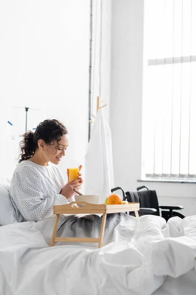 Positiva donna afro-americana che fa colazione in letto d'ospedale — Foto stock