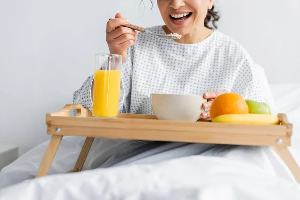 Abgeschnittene Ansicht einer lächelnden Afroamerikanerin beim Frühstück im Krankenhaus auf verschwommenem Vordergrund — Stockfoto