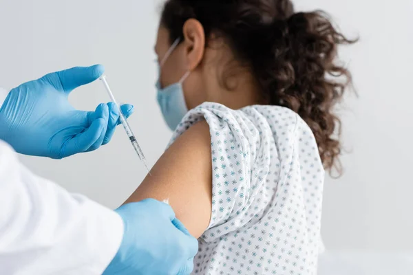 Doctor in latex gloves doing injection of vaccine to african amercan woman — Stock Photo