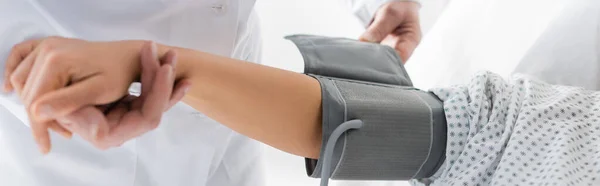 Partial view of doctor putting cuff of tonometer on hand of patient, banner — Stock Photo