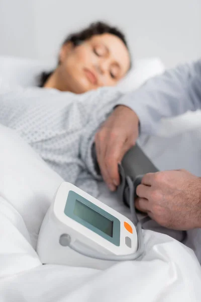 Médico medición de la presión arterial de la mujer afroamericana enferma sobre fondo borroso - foto de stock
