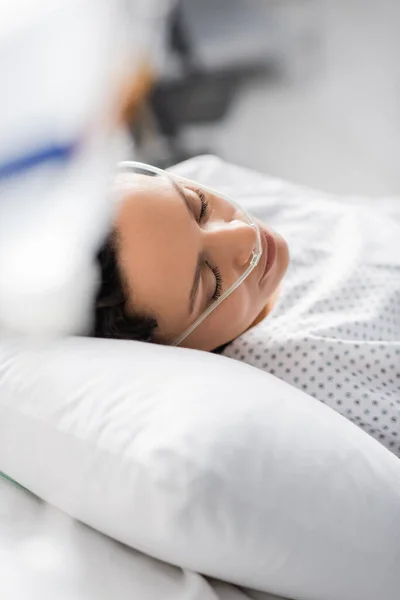 Mujer afroamericana enferma con cánula nasal durmiendo en el hospital en primer plano borroso - foto de stock