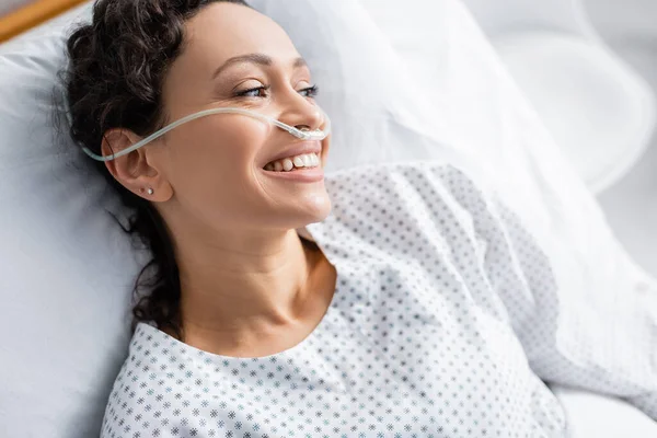 Vue aérienne de joyeuse femme afro-américaine avec canule nasale regardant loin à l'hôpital — Photo de stock