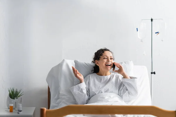 Alegre afroamericana mujer hablando por teléfono móvil en clínica - foto de stock