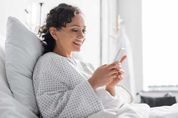 Smiling african american woman messaging on mobile phone in hospital — Stock Photo