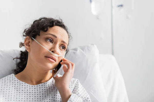 Mujer afroamericana molesta mirando hacia otro lado mientras habla por teléfono móvil en la clínica - foto de stock