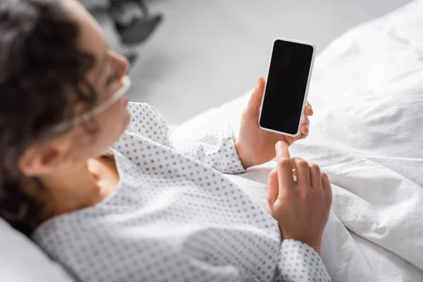 Vista ad alto angolo della donna afro-americana che tiene il cellulare con schermo bianco in primo piano sfocato — Foto stock