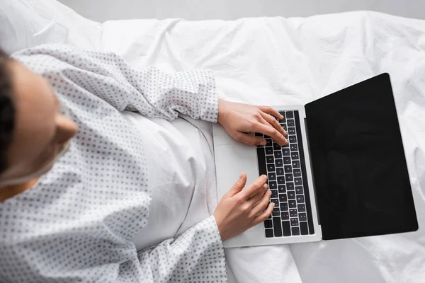 Visão aérea da mulher americana africana digitando no laptop com tela em branco na clínica, foreground borrado — Fotografia de Stock