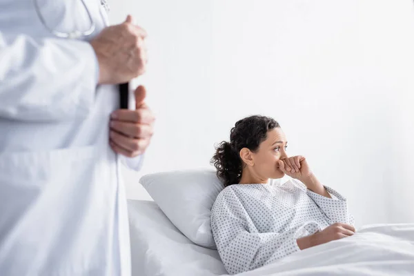 Upset african american woman looking away near doctor on blurred foreground in hospital — Stock Photo