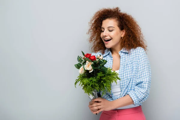 Staunte Frau im karierten Hemd mit Blumenstrauß auf grauem Hintergrund — Stockfoto