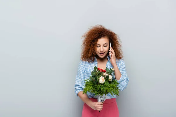 Lächelnde Frau mit Blumen, die auf dem Handy vor grauem Hintergrund anruft — Stockfoto